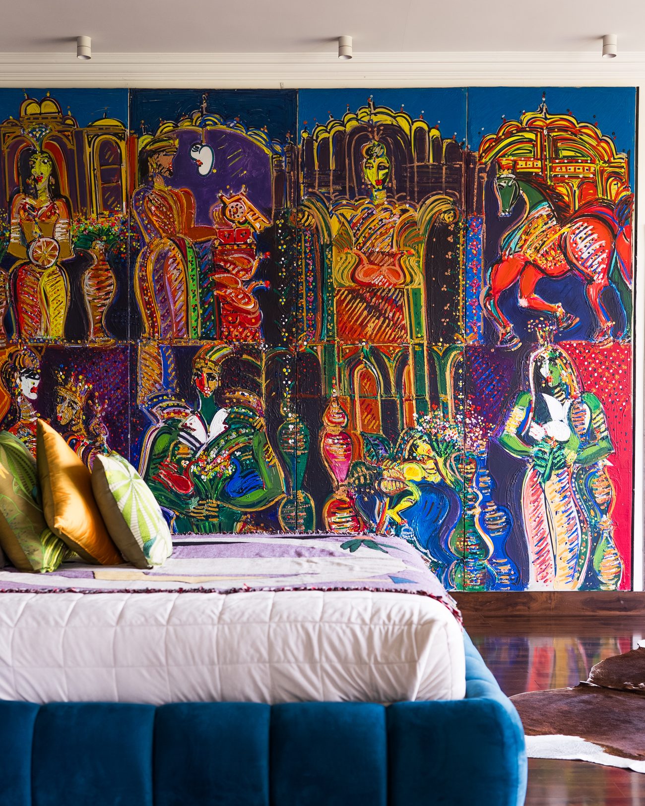 Bedroom built around a four-panel painted mural and a deep blue velvet bed