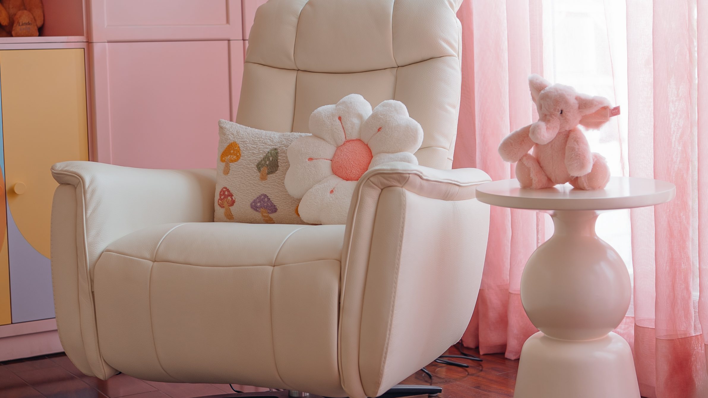 Cream reading chair by the window, with pink joinery behind