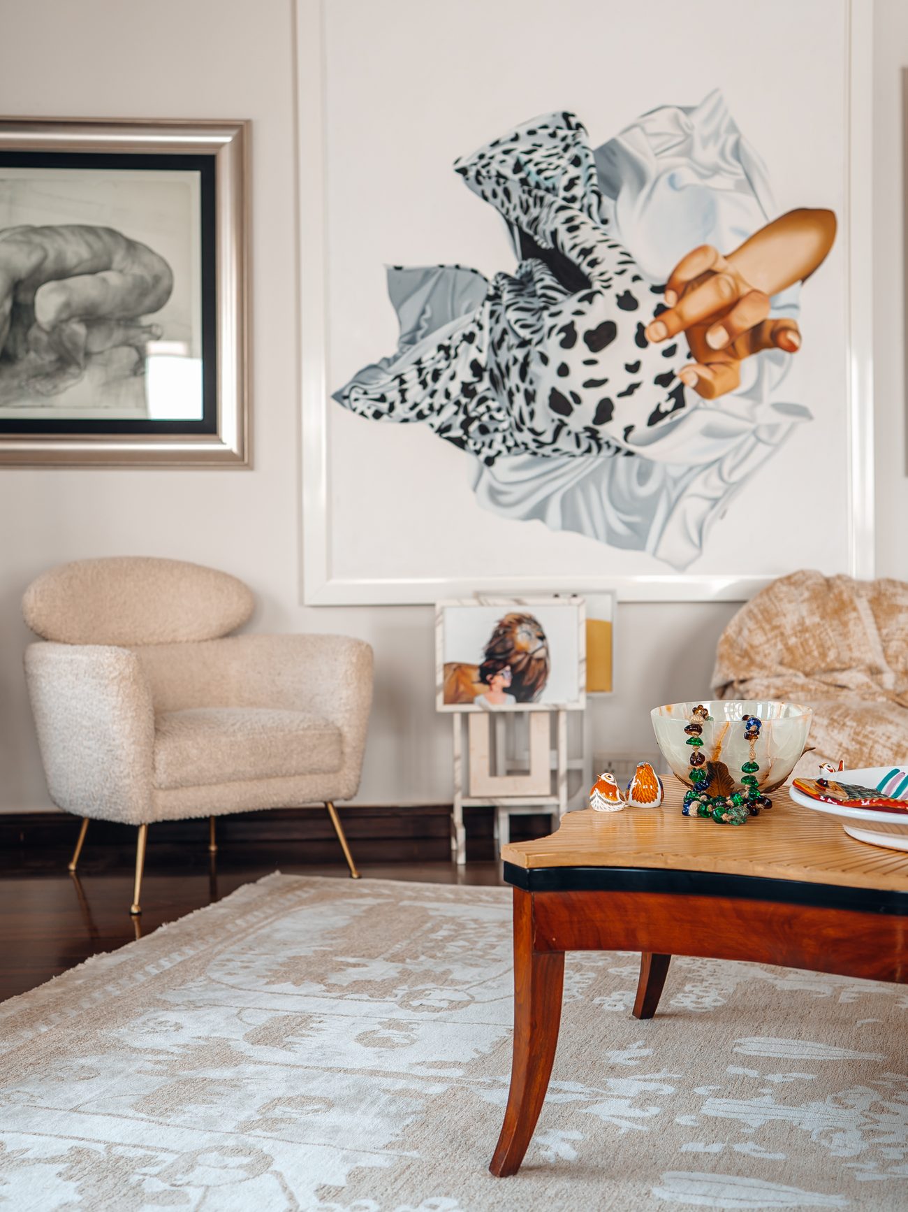 Lounge with bouclé armchairs, a carved timber table and a large painted canvas