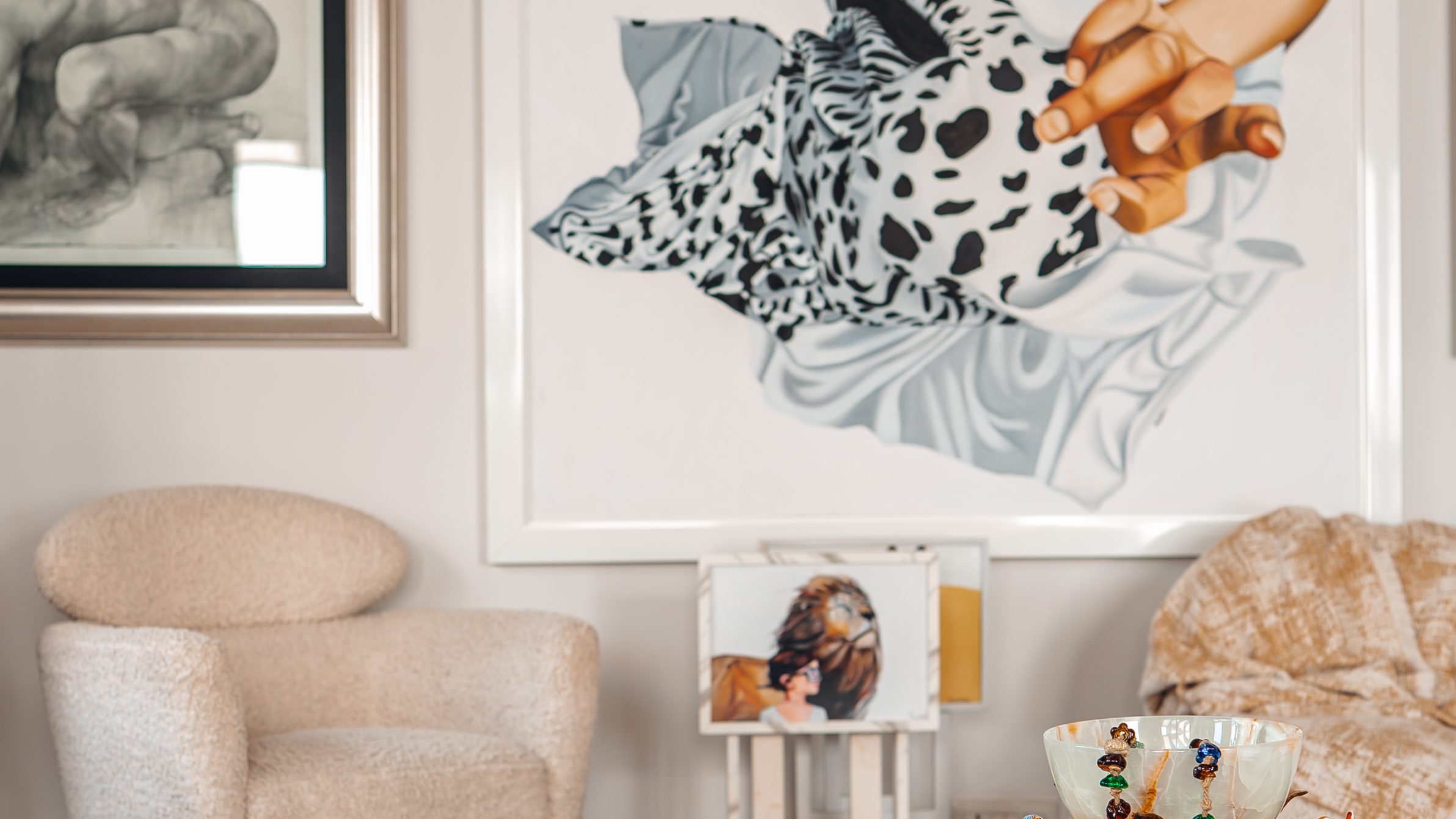 Lounge with bouclé armchairs, a carved timber table and a large painted canvas