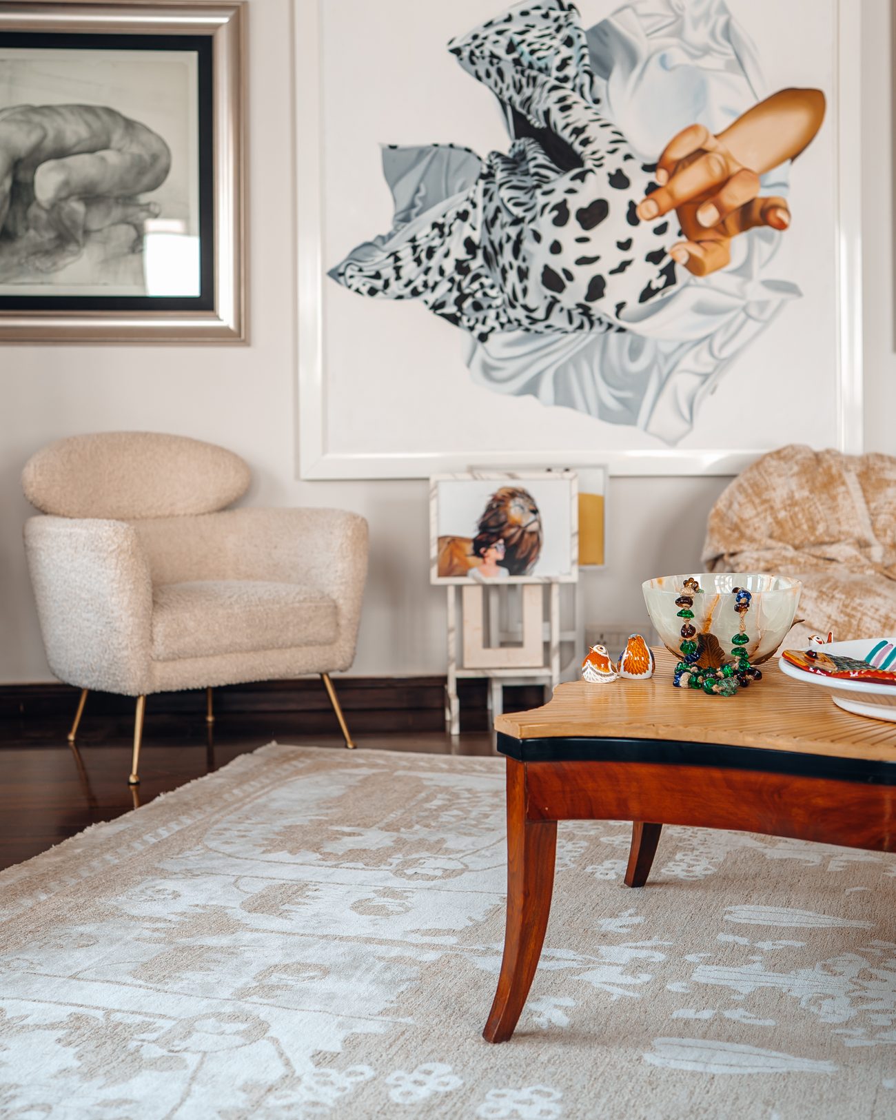 Lounge with bouclé armchairs, a carved timber table and a large painted canvas