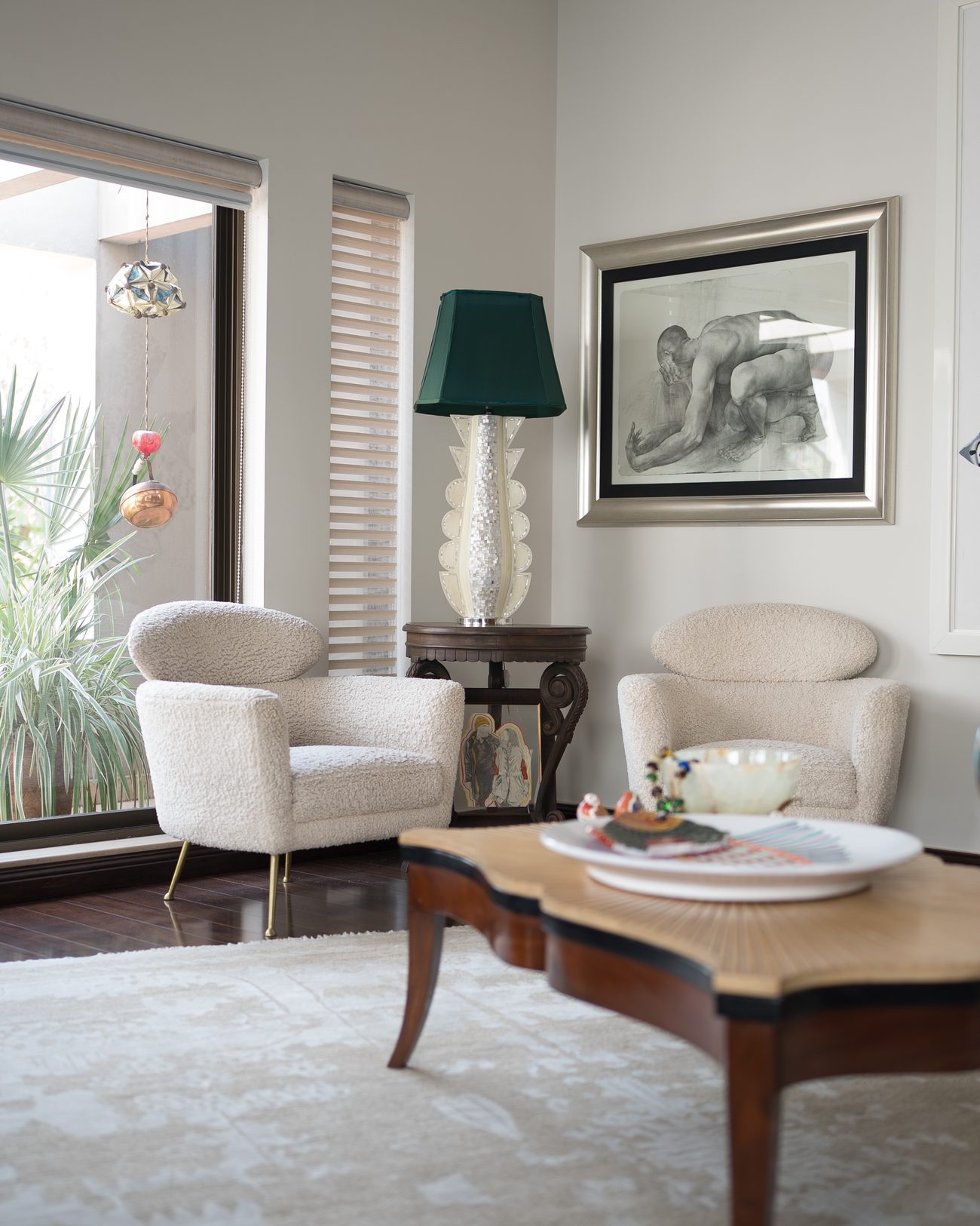Lounge with bouclé armchairs, a carved timber table and a large painted canvas