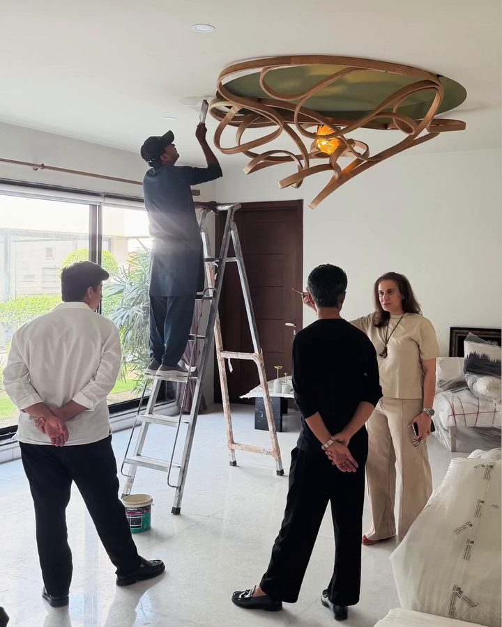 Installing a carved ribbon ceiling light while the team looks on