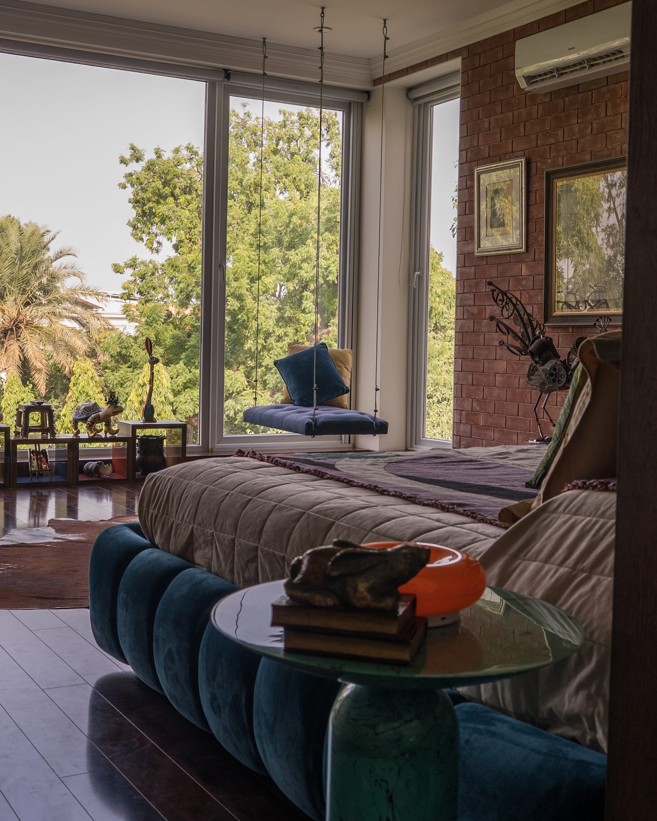 Bedroom with a deep blue velvet bed, brick wall and garden windows